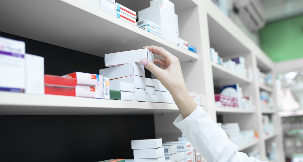 closeup-view-pharmacist-hand-taking-medicine-box-from-shelf-drug-store