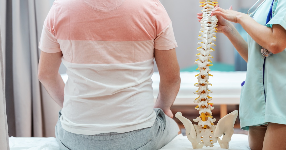 female-doctor-holding-spine-model-pointing-vertebra-while-patient-sitting-hospital-bed-her-with-backs-turned