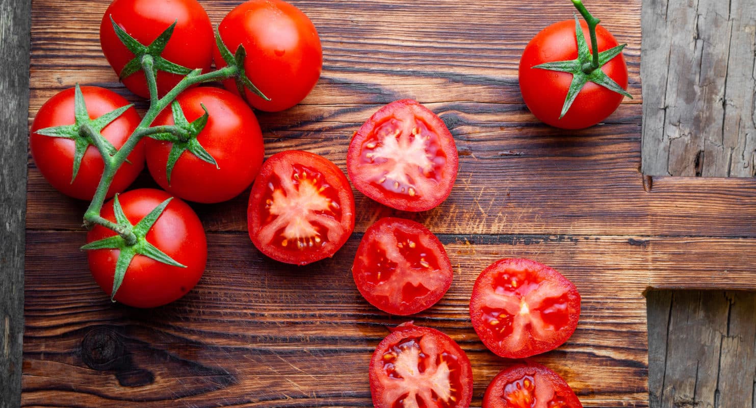 some-tomatoes-slices-with-knife-wooden-cutting-board-top-view-e1666959667595